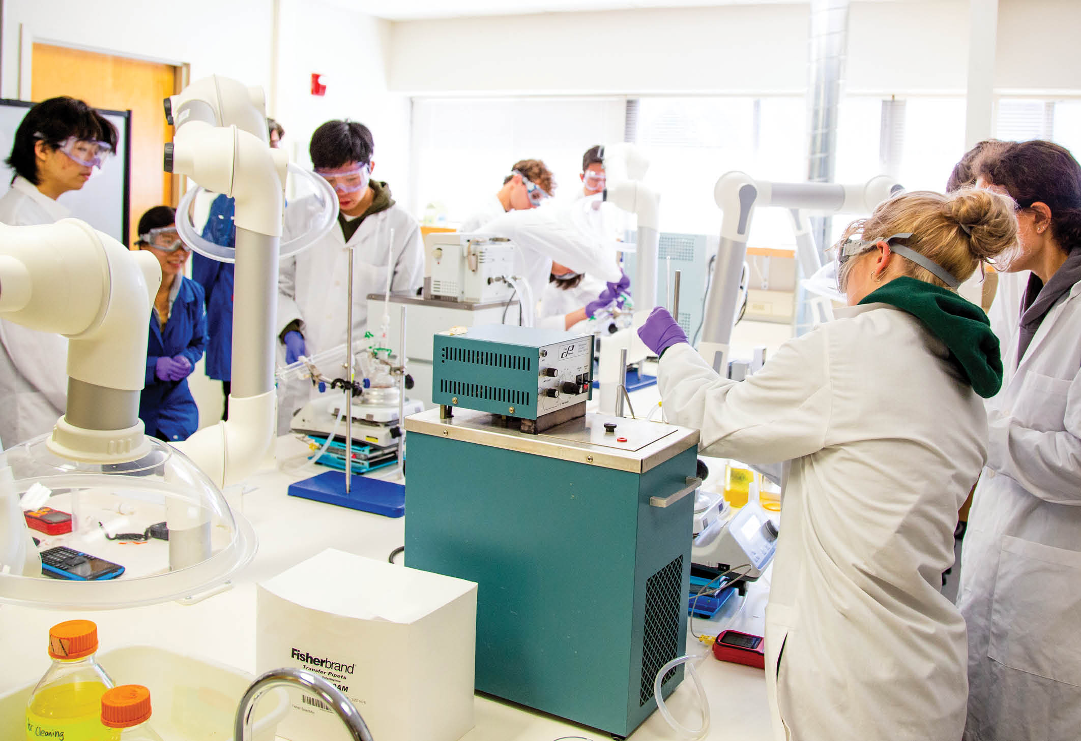 Students in lab wearing lab coats and running experiments