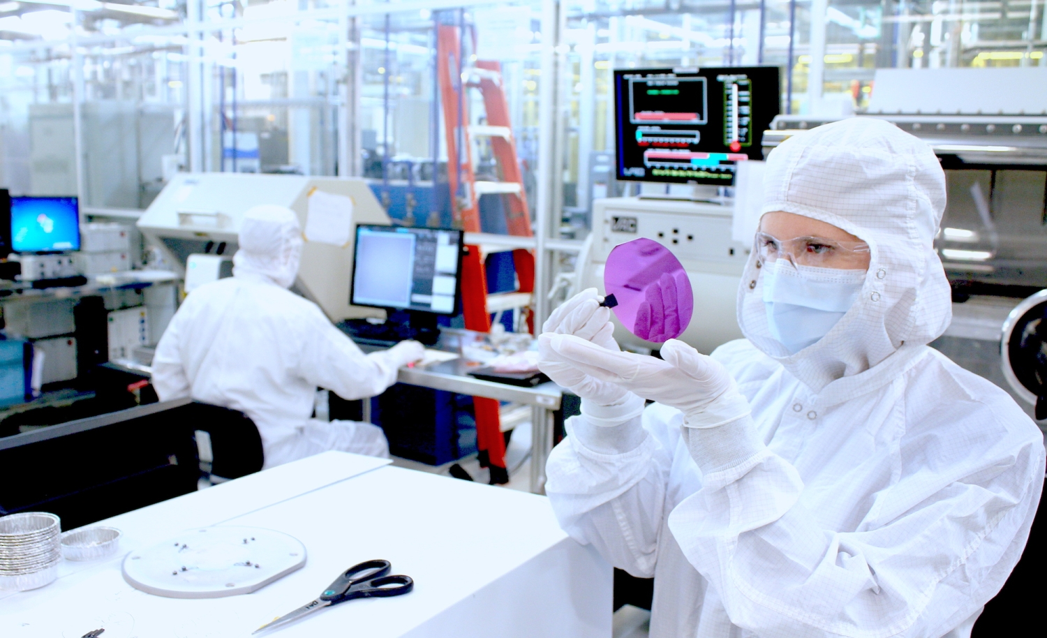 A researcher examines a wafer fabricated inside the UC Santa Barbara Nanofabrication Facility. 