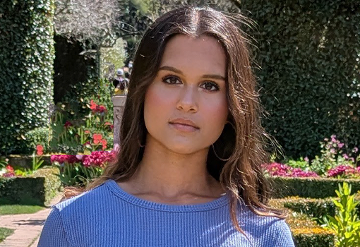 Headshot of Anika Jena, taken outside in a garden