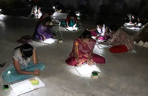 Female students in India study with solar-powered LED lights from Unite to Light.